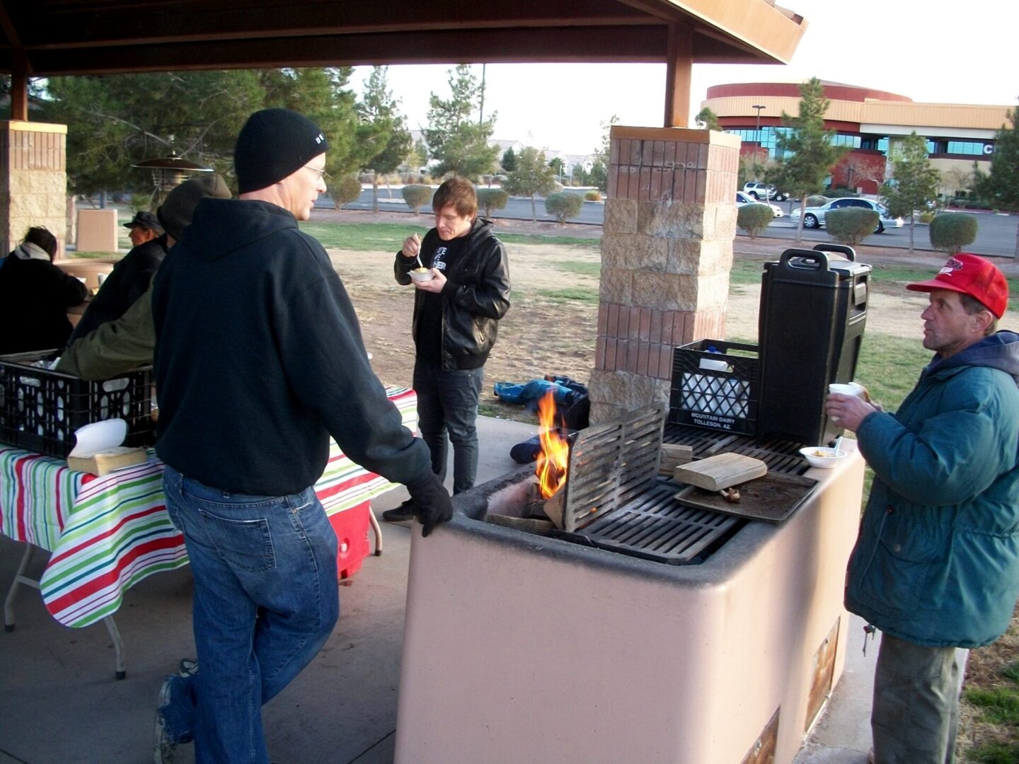 Group cooking outdoors at picnic table.